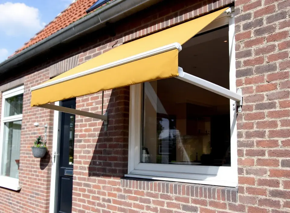Okerkleurig uitvalscherm voor een raam van een bakstenen woning: de armen duwen de onderkant van het doek naar buiten